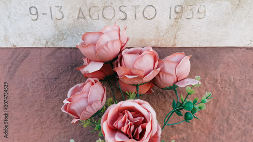 Obraz na plátně Fiori finti su monumento commemorativo rose e marmo
