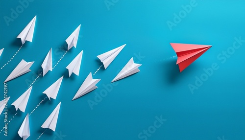 paper planes in a row on blue background and one paper glider going in different direction breaking new ground and stepping out of the line concept