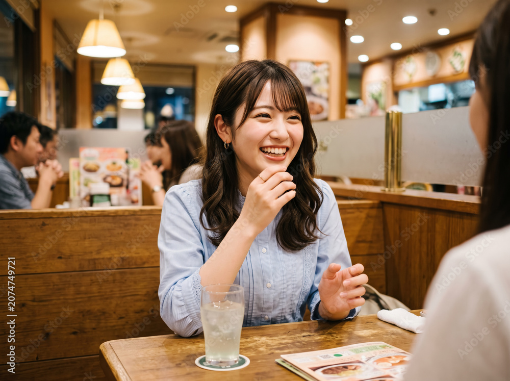 Fototapeta premium 夜のファミレスでドリンクを前に楽しそうに談笑する女性