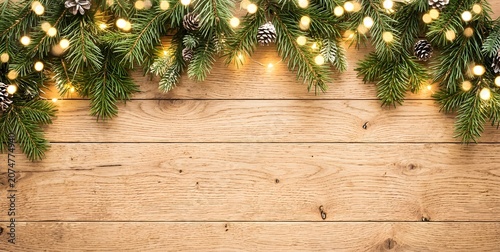Festive christmas garland on wooden background with lights and pinecones decoration