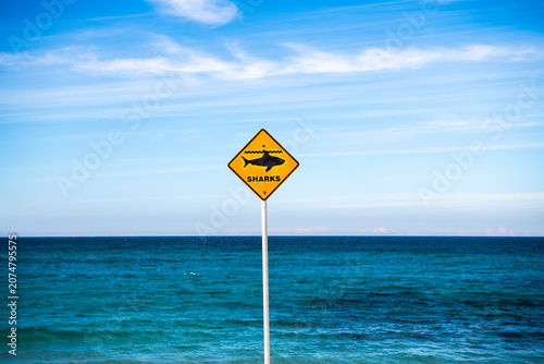 Shark warning and beach closure signs on Bronte Beach following a shark incident, with calm ocean and blue sky, Sydney, Australia.