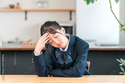 Fotografie Middle school, high school, and elementary school students in their uniforms are worried, troubled, have a fever, a cold, an infection, a headache, or are feeling unwell at home