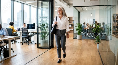 Confident mature businesswoman walking through a bright corporate office corridor