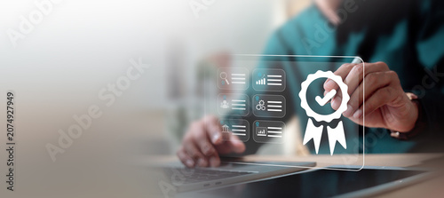 Quality assurance and ISO certification standard concept. Businessman working on laptop with digital badge icon.