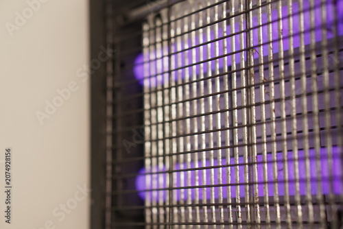 Photos Electric bug zapper featuring glowing purple UV tubes and a metal safety grid