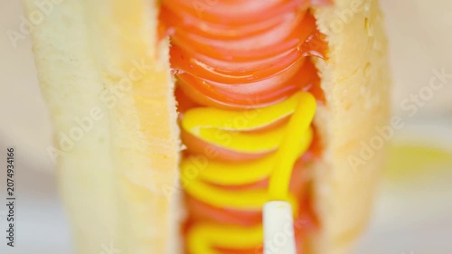 Squirting Mustard onto a Delicious Sausage Hot Dog in a Bun, Close-Up Vertical Video