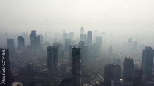 High-angle aerial view of modern city skyscrapers completely enveloped in dense white morning fog.