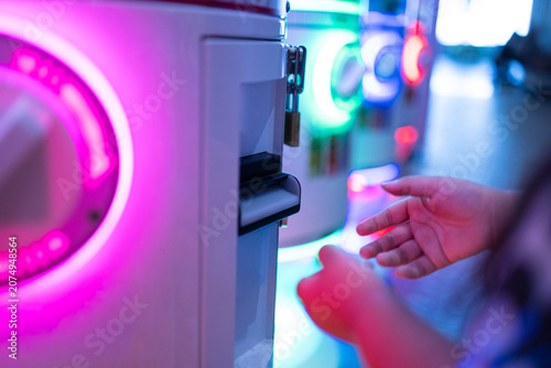 Foto Neon Gachapon Vending Machine and Hand Interaction,A close-up of a person's hand