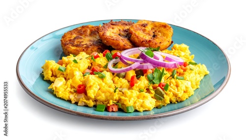 A vibrant, close-up photograph displays a colorful breakfast plate with scrambled eggs, fried plantains, and fresh onion rings