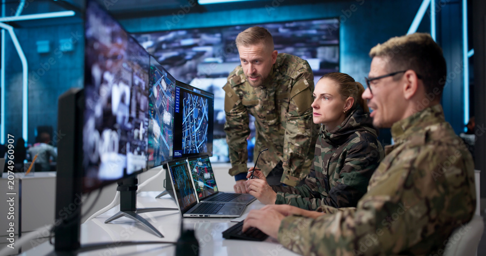 Fototapeta premium Military Intelligence Team Monitors Missions Using Laptops