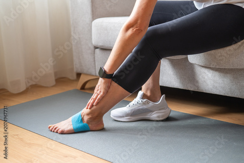 Foto Woman sitting on a sofa, performing foot rehabilitation exercises with kinesiolo