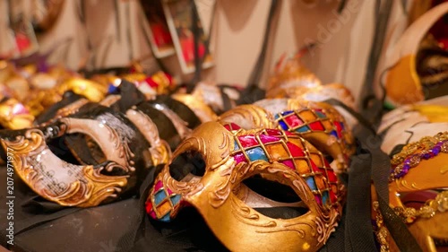 Close-up of beautiful traditional carnival masks on display in a souvenir shop. Slow camera push-in on an ornate gold and colorful harlequin masquerade mask