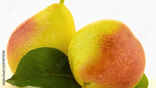Fresh organic pears rotating on a white surface. Vibrant yellow and red fruits with green leaves and water drops. Perfect for diet, nutrition, or culinary themes