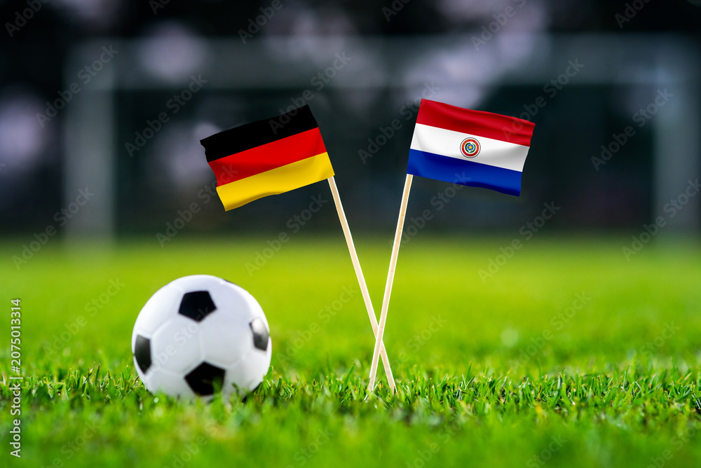 Obraz premium Germany vs Paraguay, national flags before international football tournament Round of 32 match, football on green grass with goal in the background, Foxborough, Massachusetts, USA, June 29, 2026