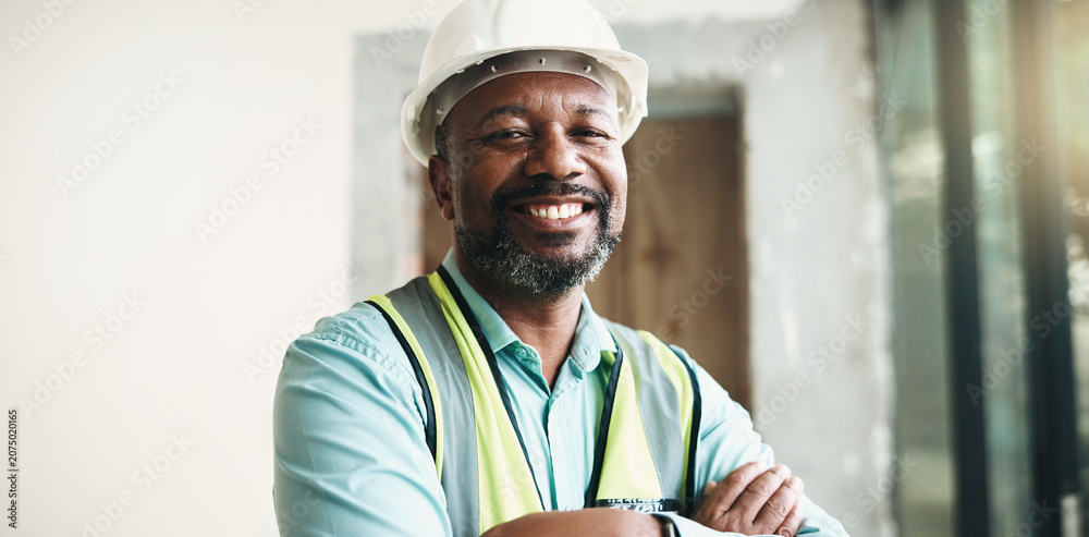 Obraz premium Crossed arms, black man and portrait of construction worker on site with confidence for renovation. Smile, about us and mature civil engineer with pride for repairs, maintenance or building project.
