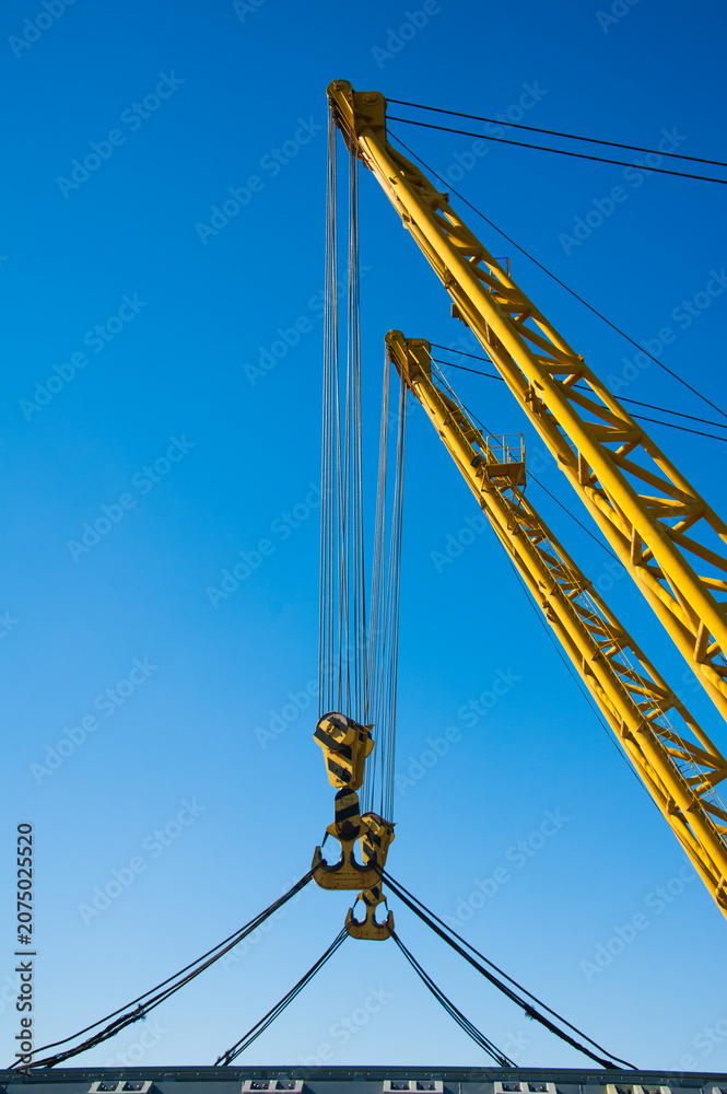 Fototapeta premium Loading in port. Floating port crane on blue sky background