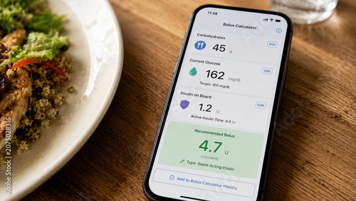 Close-up of a smartphone screen showing a diabetes bolus insulin dose calculator app, displaying carbohydrate entry, current glucose level, and recommended insulin dose