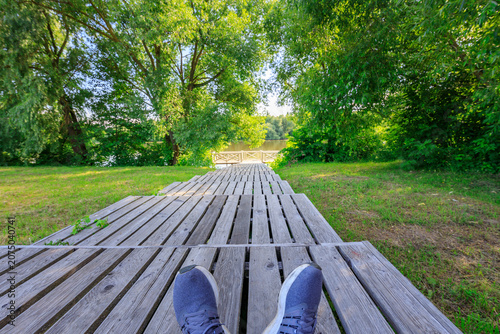 Принти на полотні First-person view: feet on wooden deck, surrounded by verdant trees and grass