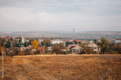 A golden autumn meadow in the foreground with a small village in the background.