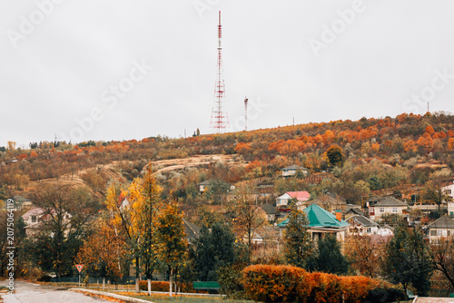 A small village surrounded by colorful autumn trees under a clear blue sky.