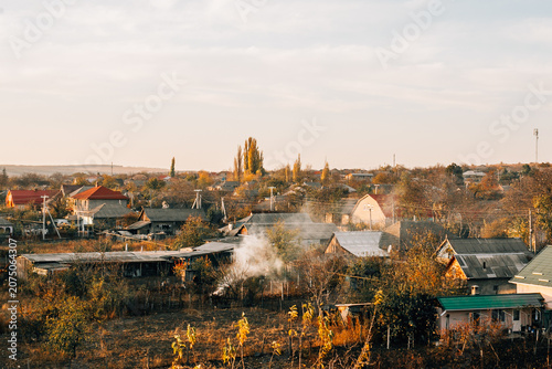 A quiet village with golden autumn trees and open fields.