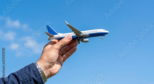 hand holding small model airplane against blue sky