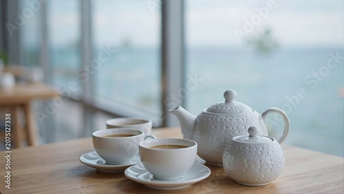 White tea set with cups and teapot on a wooden table