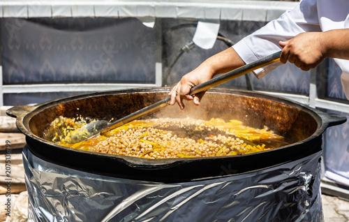 Foto Chef cooking traditional Uzbek pilaf in a giant cauldron at a food festival
