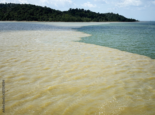 Фотография Serpentine water boundary line of muddy river silt meeting ocean water