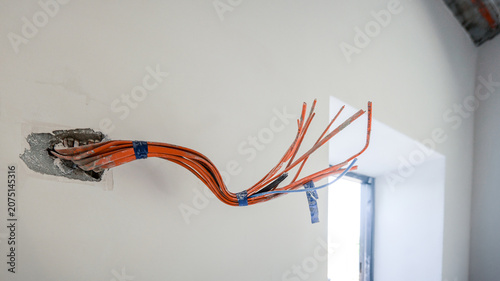Fotografie Exposed electrical wiring bundle emerging from a wall opening during constructio