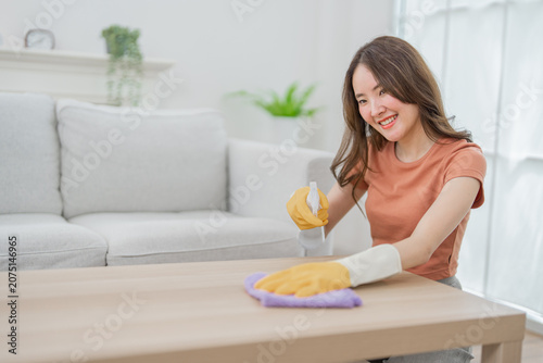 Woman cleaning glove table spray cloth home living room smile hygiene cheerful young woman wearing rubber glove cleaning wooden table with spray bottle and cloth in bright living room