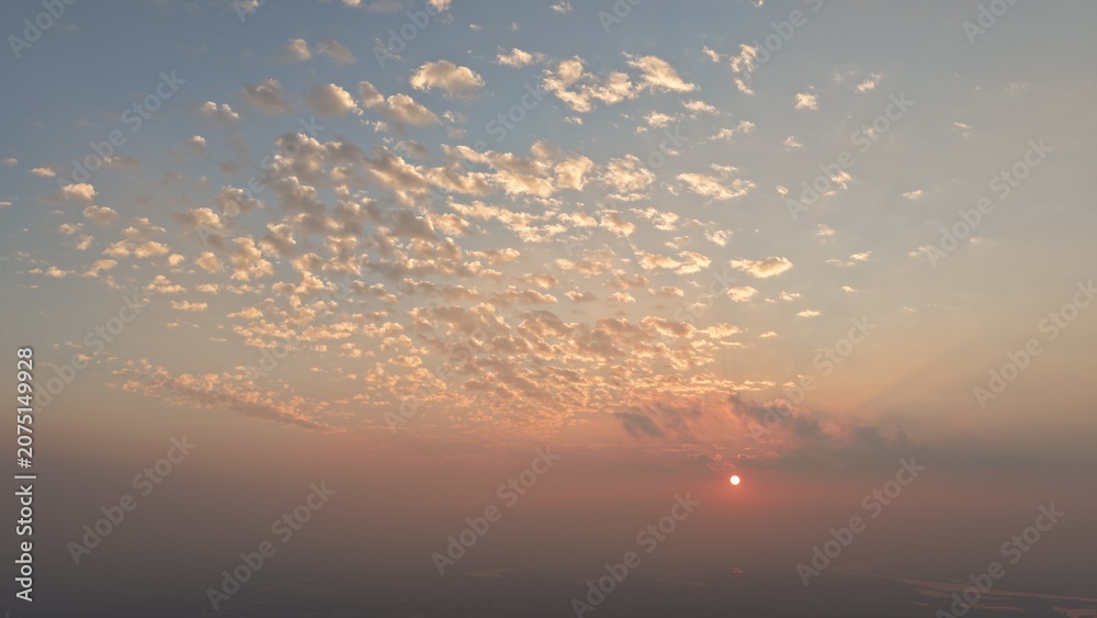 Fototapeta premium High Elevation Static Shot Glowing Scattered Pastel Clouds Sunrise Hazy Horizon Sky