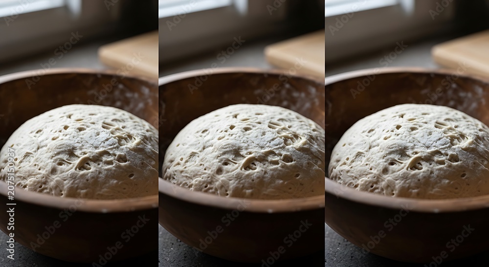 Fototapeta premium Fresh raw bread dough rising in a wooden bowl on a kitchen table