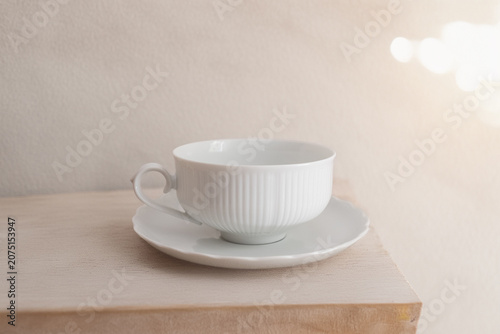 White porcelain teacup and saucer on a minimalist beige background