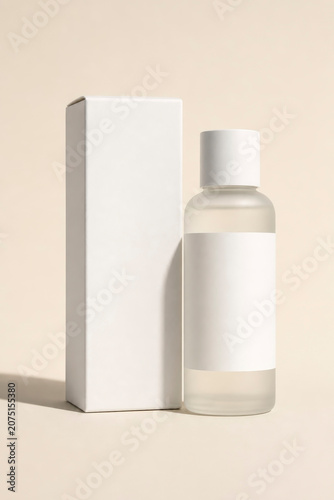 Blank frosted glass cosmetic dropper or lotion bottle mockup standing next to a white cardboard packaging box on a minimalist beige background, studio product shot