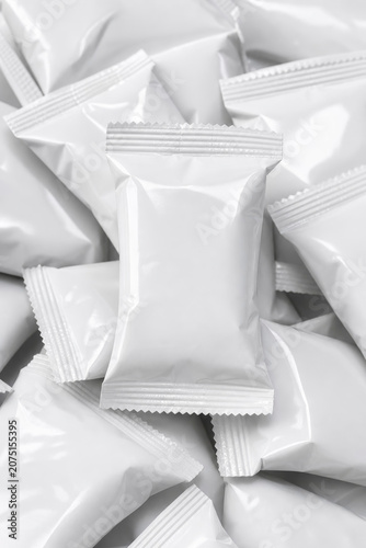 High-angle pile of multiple blank white plastic snack packets or candy pillows, showcasing a clean packaging design mockup for food products