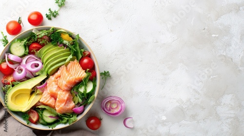 fresh salad bowl with avocado, salmon and vegetables on bright table