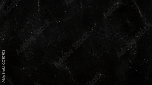 Fotografie Dark scratched black background with white specks and scratches texture