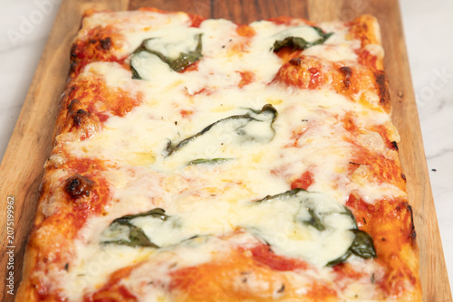 Cuadro en lienzo Pizza rectangulaire avec sauce tomate et fromage sur une planche en bois