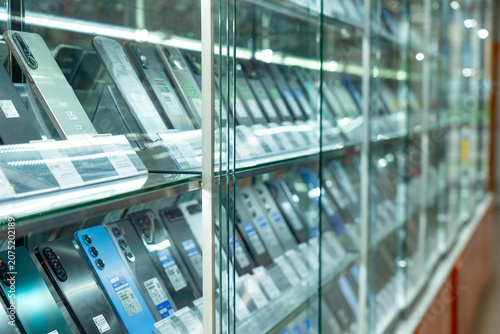 A Display Showcase of Modern Smartphones Featuring Various Models and Colors Behind Glass in a Retail Setting.