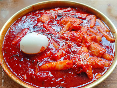 delicious bowl of Korean spicy rice cakes (tteokbokki) served with fish cakes, a boiled egg, and sesame seeds in a rich red chili sauce. 