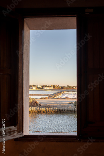 Famous salt flats of Marsala with windmill at golden hour