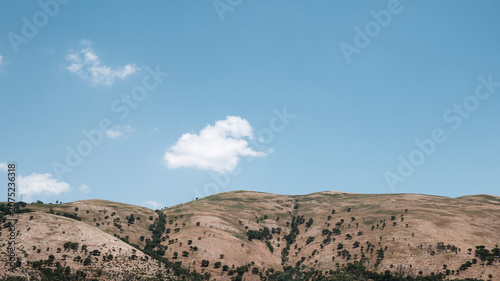 Landscape of Arid Hills Under a Broad Blue Sky with Clouds
