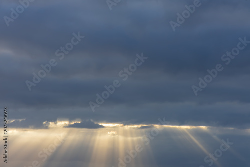 Photography Dramatic crepuscular sunbeams breaking through heavy storm clouds over the ocean
