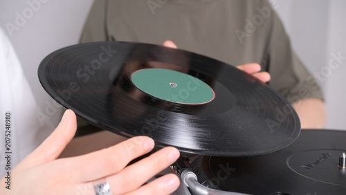 Tableau sur toile Hands carefully placing a black vinyl record with a green label onto a modern re