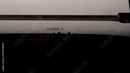 Bild auf Leinwand Typewriter carriage holding a sheet of white paper with the words chapter i typed in the center