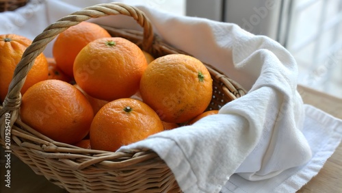 Organic juicy orange fruits displayed in a traditional basket with elegant white cloth creating a fresh healthy food concept