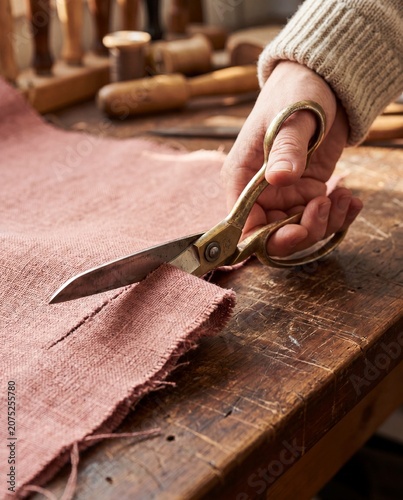 Hand cutting dusty rose upholstery fabric with shears macro reupholstery restoration
