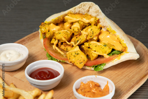 Foto Sandwich poulet curry avec sauce sur un plat en bois