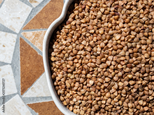 Fresh organic uncooked buckwheat in gray plate on the table for cooking.